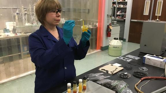 A scientist in a lab looking at a substance in a beaker.