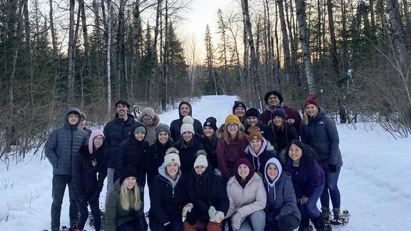 A group of college students in the woods in winter.