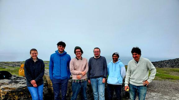 A group of six students on a blustery day in the field on their study abroad trip to Ireland