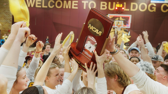 Hands reach for a NCAA trophy in front of the Welcome to Bulldog Country Sign