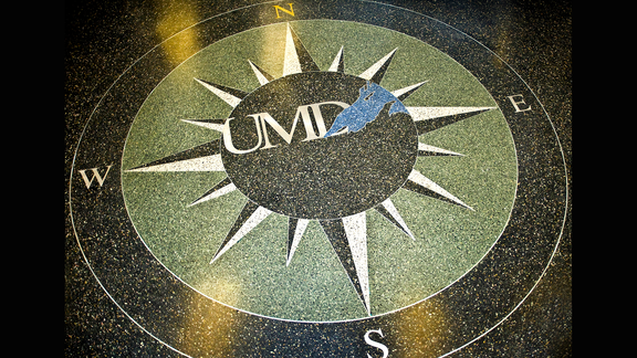 A terrazzo floor with an inlay of a compass with UMD and the shape of Lake Superior