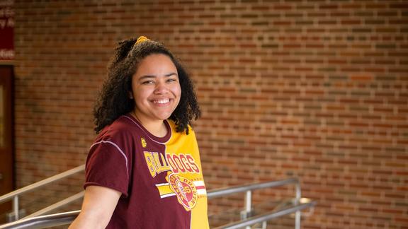 Olivia Osei-Tutu wearing a maroon and gold Bulldogs t-shirt standing at the top of some stairs
