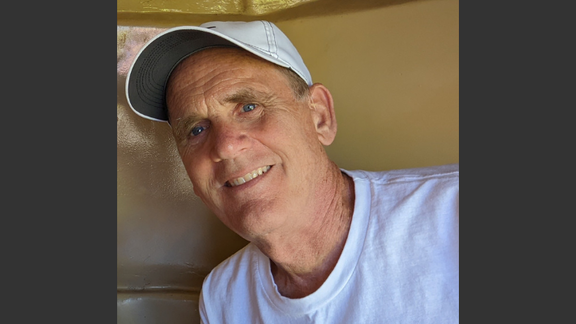 Kent Brorson, smiling and wearing a white shirt and ball cap