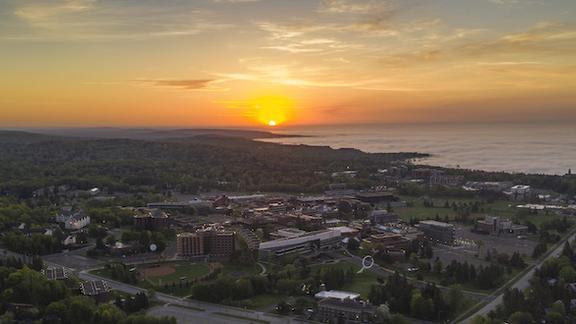 A drone shot of sunrise over Lake Superior and the UMD campus.