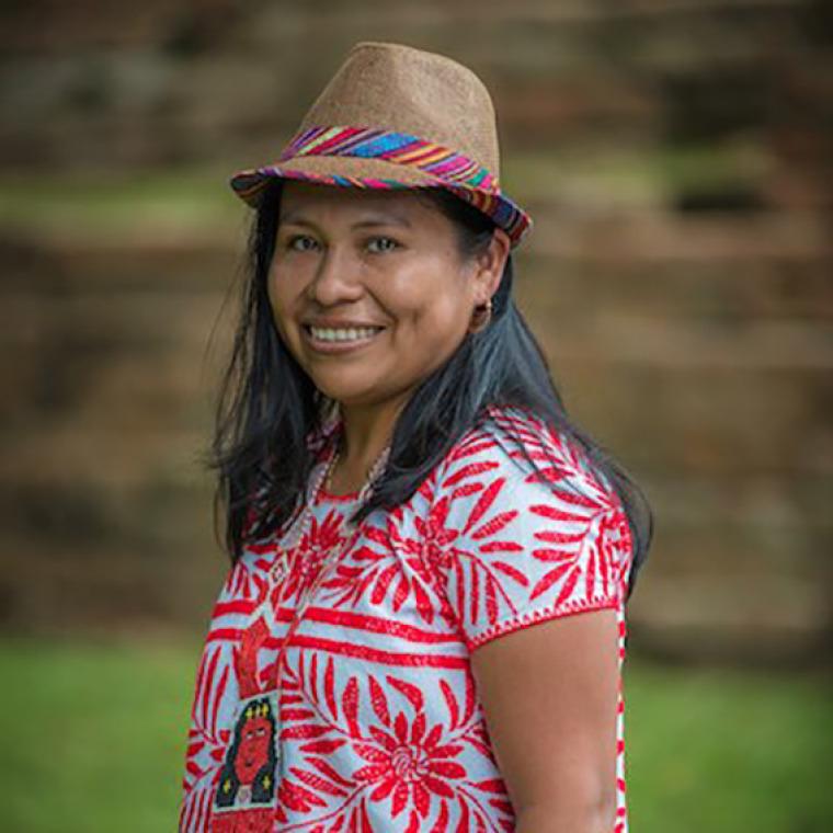 Cristina Coc smiling with a hat and red flowered shirt.
