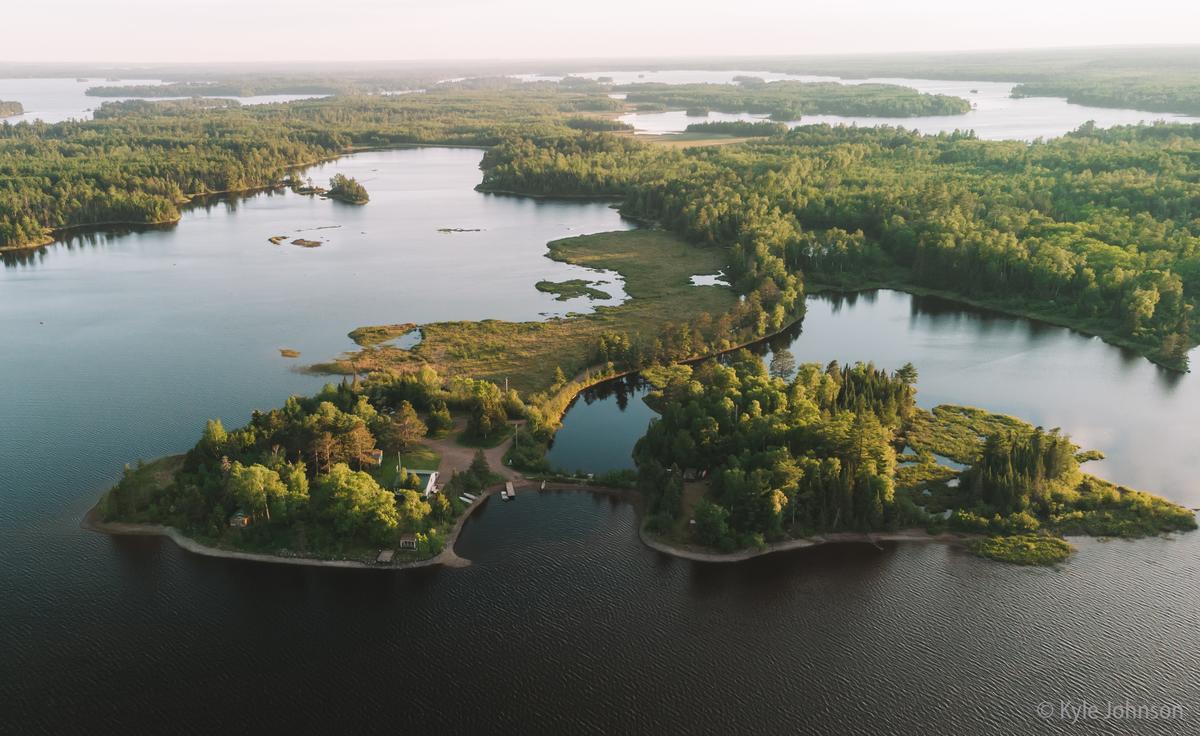 A drone shot of a lake with a peninsula and a small island.