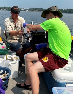 Two scientists on a boat working with water samples.