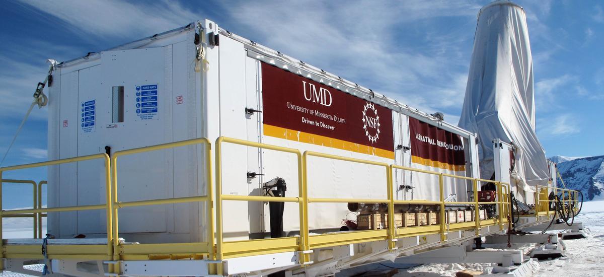 A white trailer with banners for the University of Minnesota Duluth, in a snowy landscape.