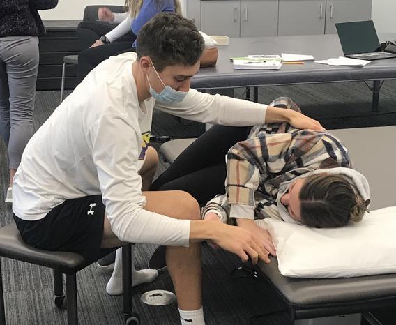 A student doing a simulated medical exam on another student.
