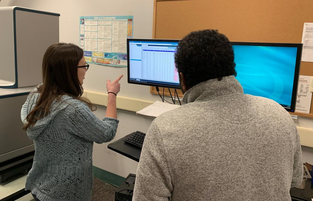 Two scientists looking at data on a computer screen.