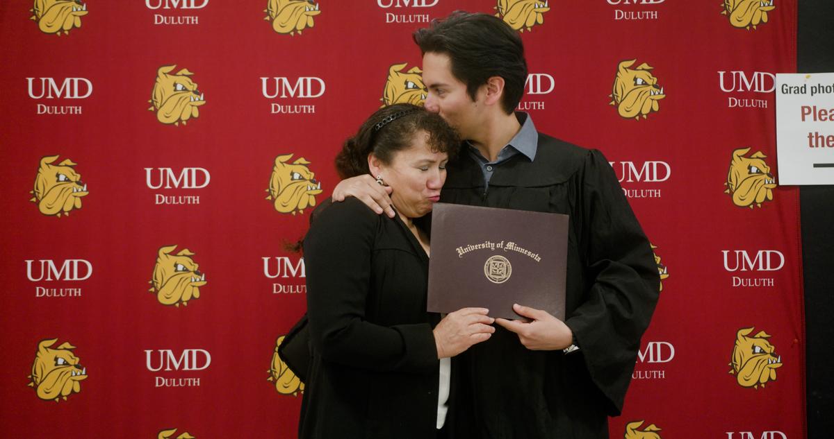 Graduate embraces his mom with his diploma