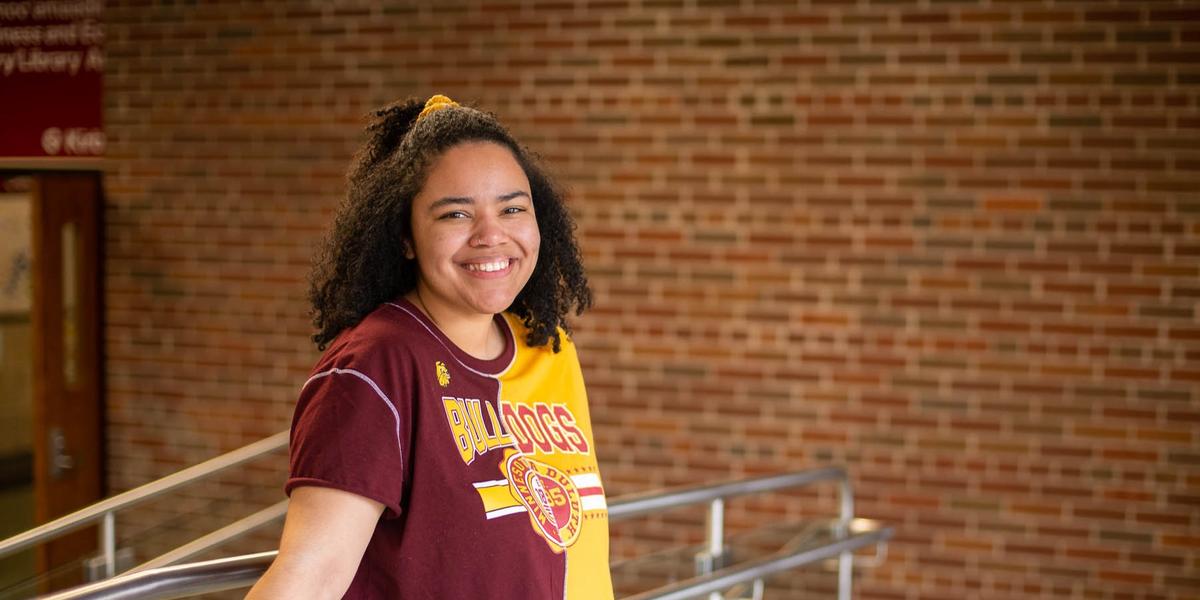 Olivia Osei-Tutu wearing a maroon and gold Bulldogs t-shirt standing at the top of some stairs