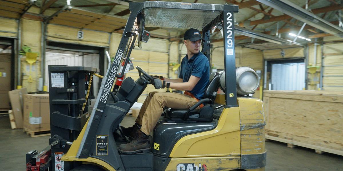 Brandon Stachewicz looks over his shoulder to back up a forklift at Dayton Freight