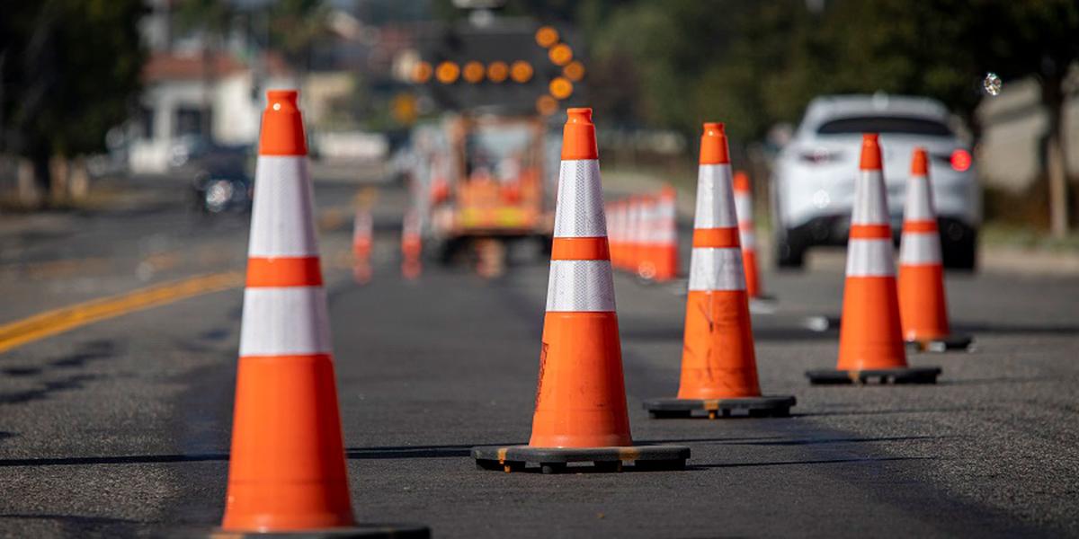 A photo showing a road construction zone with a series of traffic cones and a right arrow.