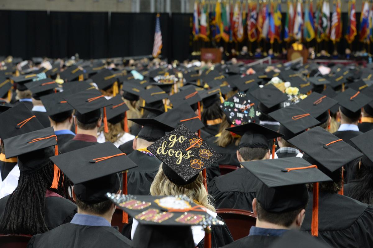 UMD students in caps and gowns. One cap is decorated with the words "Go Dogs"