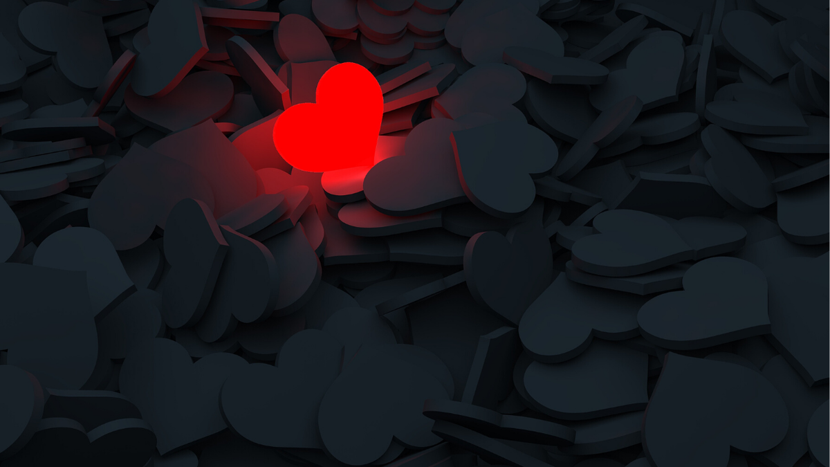 Stock photo of one red heart surrounded by all black hearts