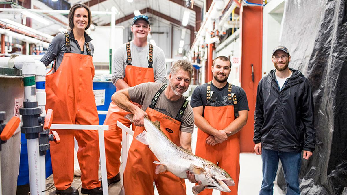 Five people standing, one is holding a large fish. Photo credit: UW-Stevens Point Northern Aquaculture Demonstration Facility.