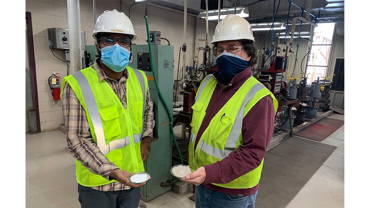 Two Natural Resources Research Institute scientists wearing masks hold alternative binders
