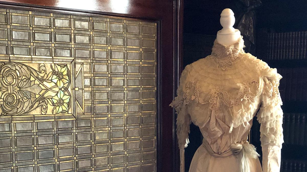 Ivory colored gown on a mannequin in front of a Glensheen fireplace