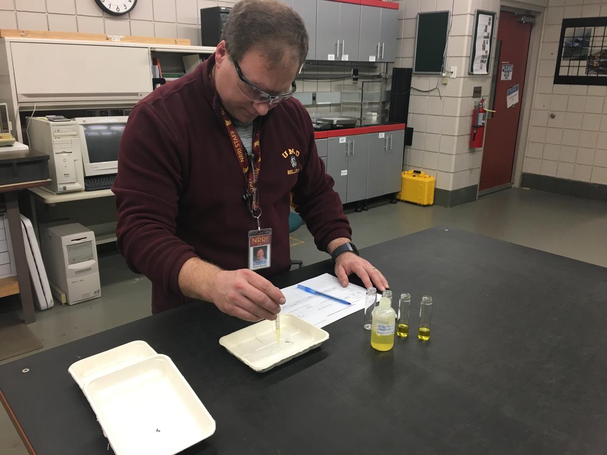 NRRI researcher picking up liquid from a tray using an eyedropper.
