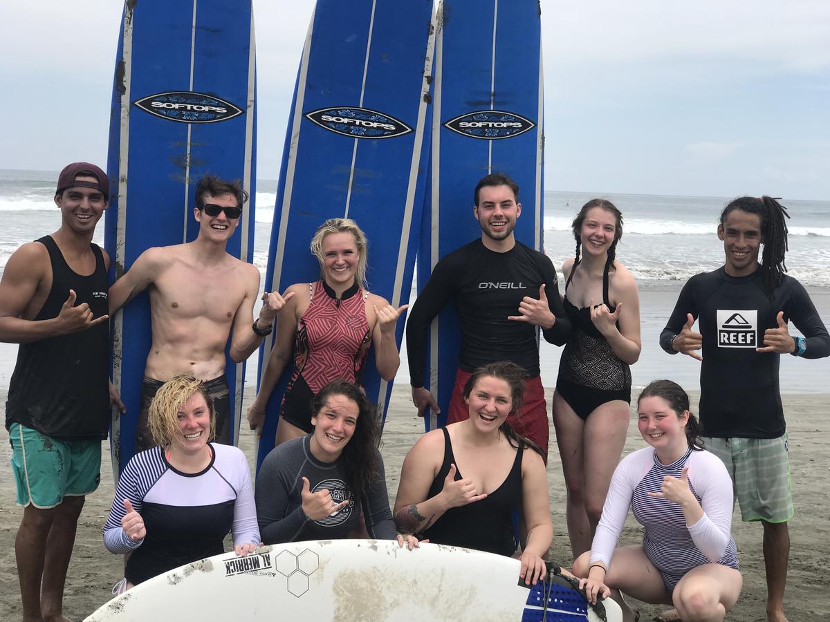Ten UMD study abroad students posing on a beach with their surf boards