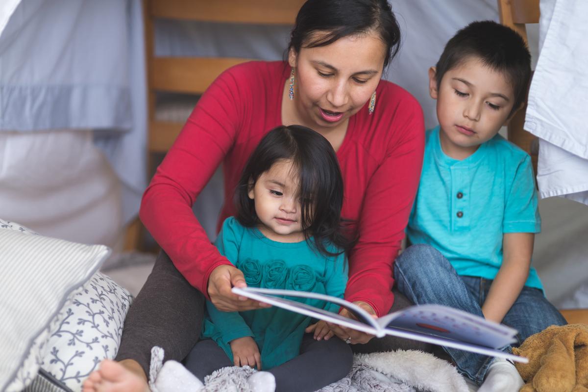 American Indian woman reading to a young boy and girl