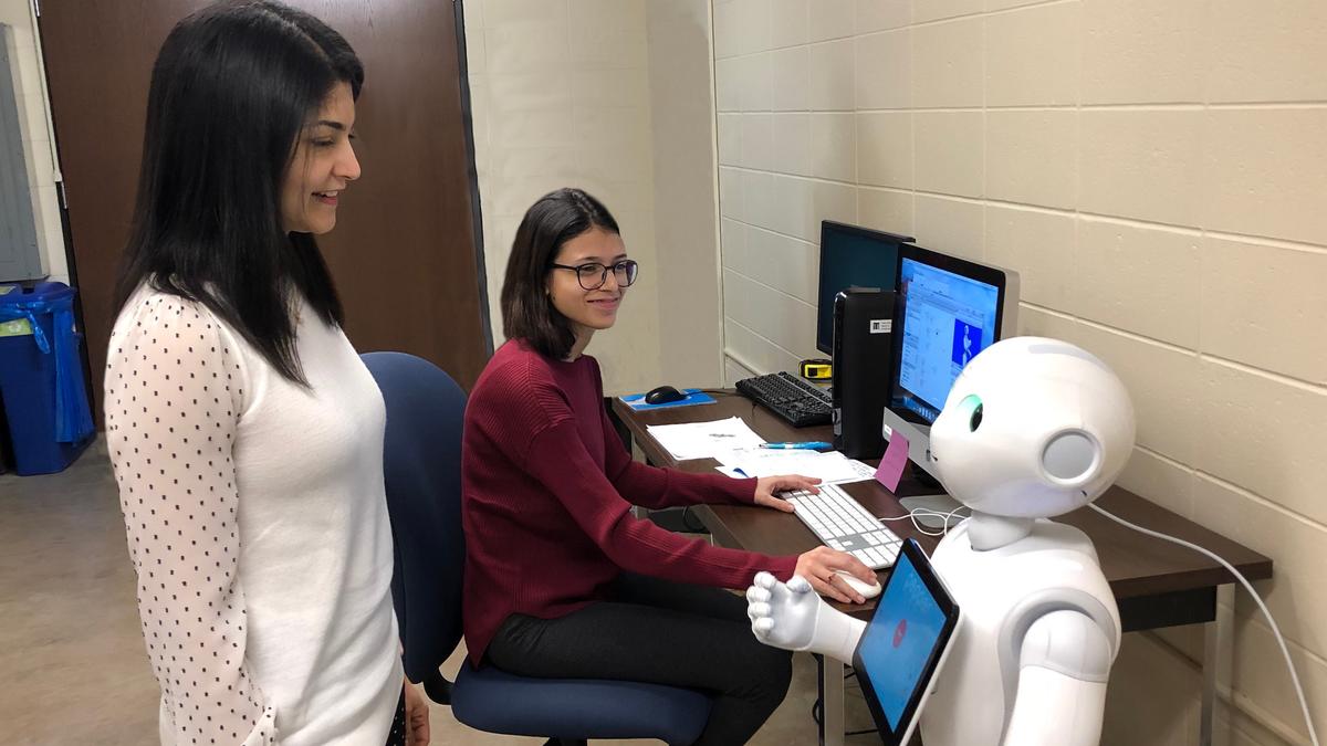 Dr. Arshia Kahn and Yumna Anwar with the robot Pepper