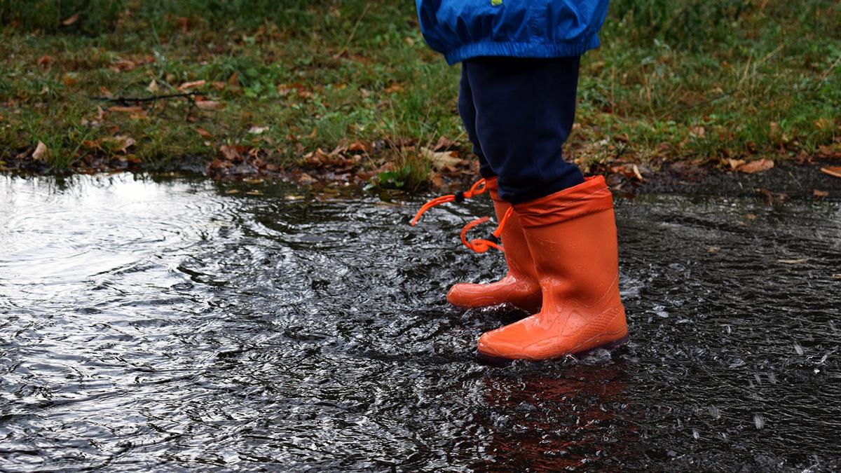 Person standing in puddle wearing red boots