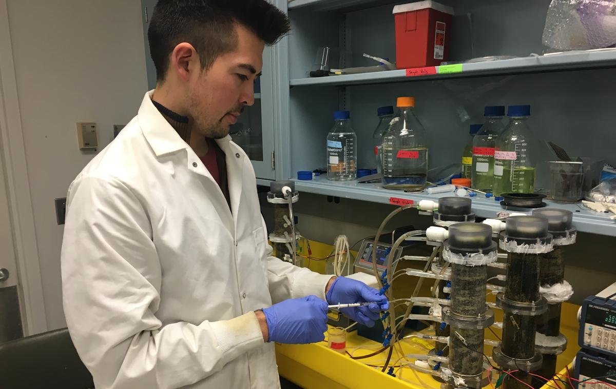 UMD student Daniel Takaki wearing a lab coat working in a lab.