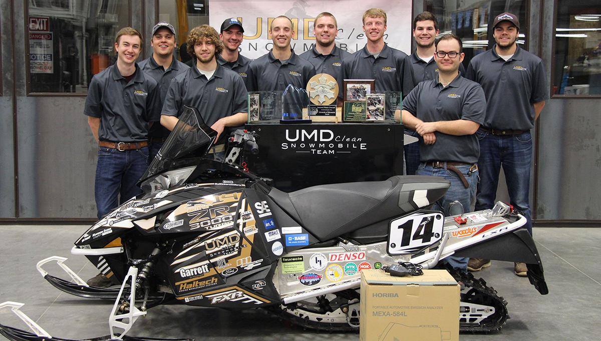 UMD's 2017 Clean Snowmobile Team standing by their snowmobile and trophies