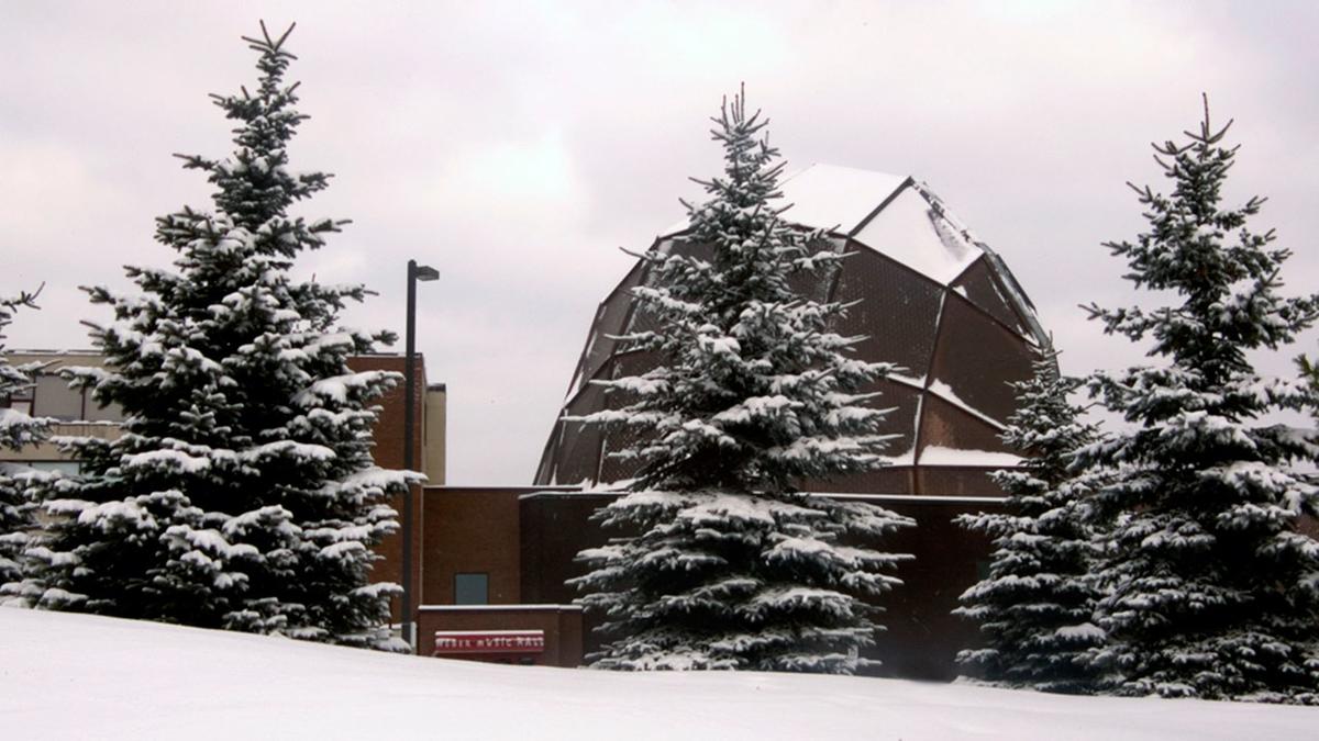 UMD's Weber Music Hall in the winter with snow-covered pines