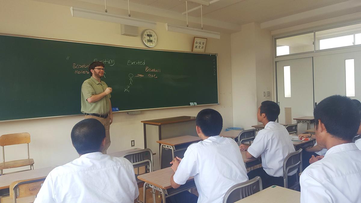 UMD Alumnus Zach Lunderberg standing before his class in Japan.