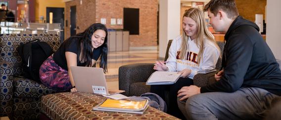 Three students sitting around a laptop with notebooks in the Kirby Student Center