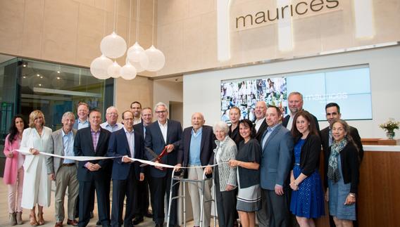 A bunch of people stand behind a ribbon in the then-new Maurices building for the ribbon cutting ceremony