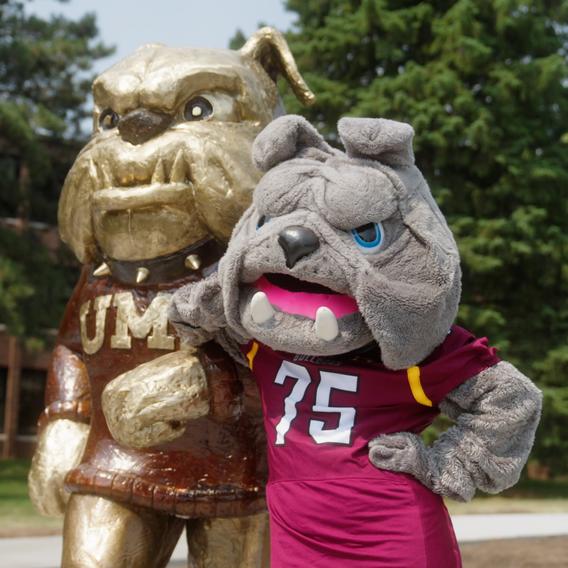 Champ the mascot leans against Champ the statue in a jaunty pose