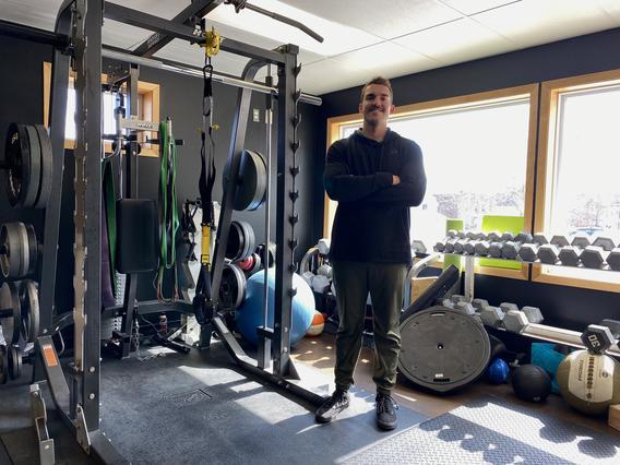 Peter stands in his gym, surrounded by equipment.