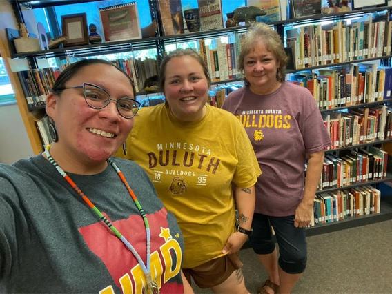 Iris Carufel, Brooke Lunski and Jody O'Connor, posing in front of a shelf of books in the American Indian Learning Resource Center