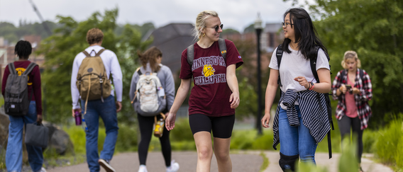 UMD students walking along campus with Weber Music Hall in the background. 