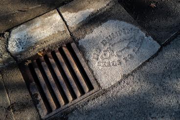 A Duluth storm drain with a fish stencil and the words "no dumping drains to lake"