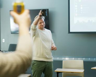 Aaron Boyson, associate professor and head of the communication department, raises his coffee cup in a toast to his department in a classroom in AB Anderson Hall.