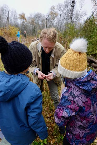 Moss Schumacher looks at a mushroom with two students