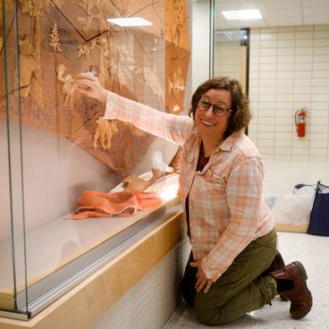 Anna Metcalfe smiles at the camera while installing her ceramic artwork titled “Reliquary of the North Shore” at the University of Minnesota Duluth.