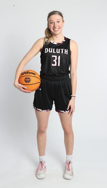 Ella Gilbertson holding a basketball and wearing a team uniform