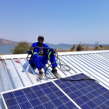 A worker in Mundulundulu Village, Siavonga, Zmbia helps install a solar system.