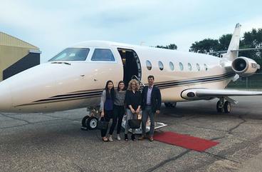 UMD student Maggie Zheng standing in front of a private jet with three coworkers
