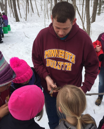 AISES student Aaron Moller showing students how a maple tap was made (photo credit: Marne Kaske)