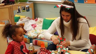UMD student and a young child wrap a gift together