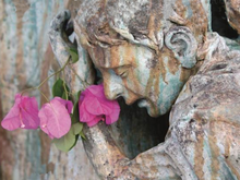 Aged statue of a person weeping with flowers