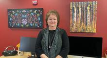 Director Jody O'Connor with new artwork in the background: “Black Floral” by Leah Yellowbird, First Nations Algonquin-Metis, and “Birch Bark Women” by Karen Savage-Blue, Fond du Lac Band of Ojibwe